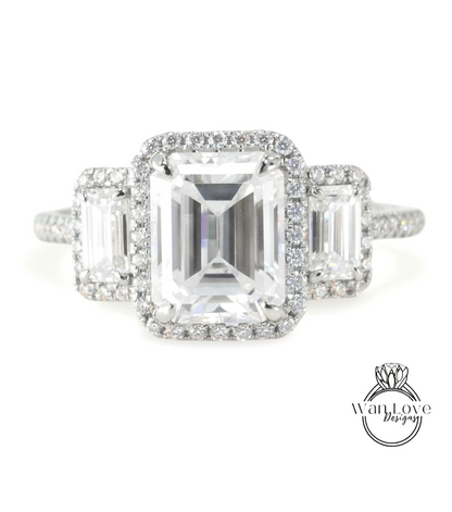 A close-up of a diamond engagement ring with a large central diamond surrounded by smaller diamonds on either side.