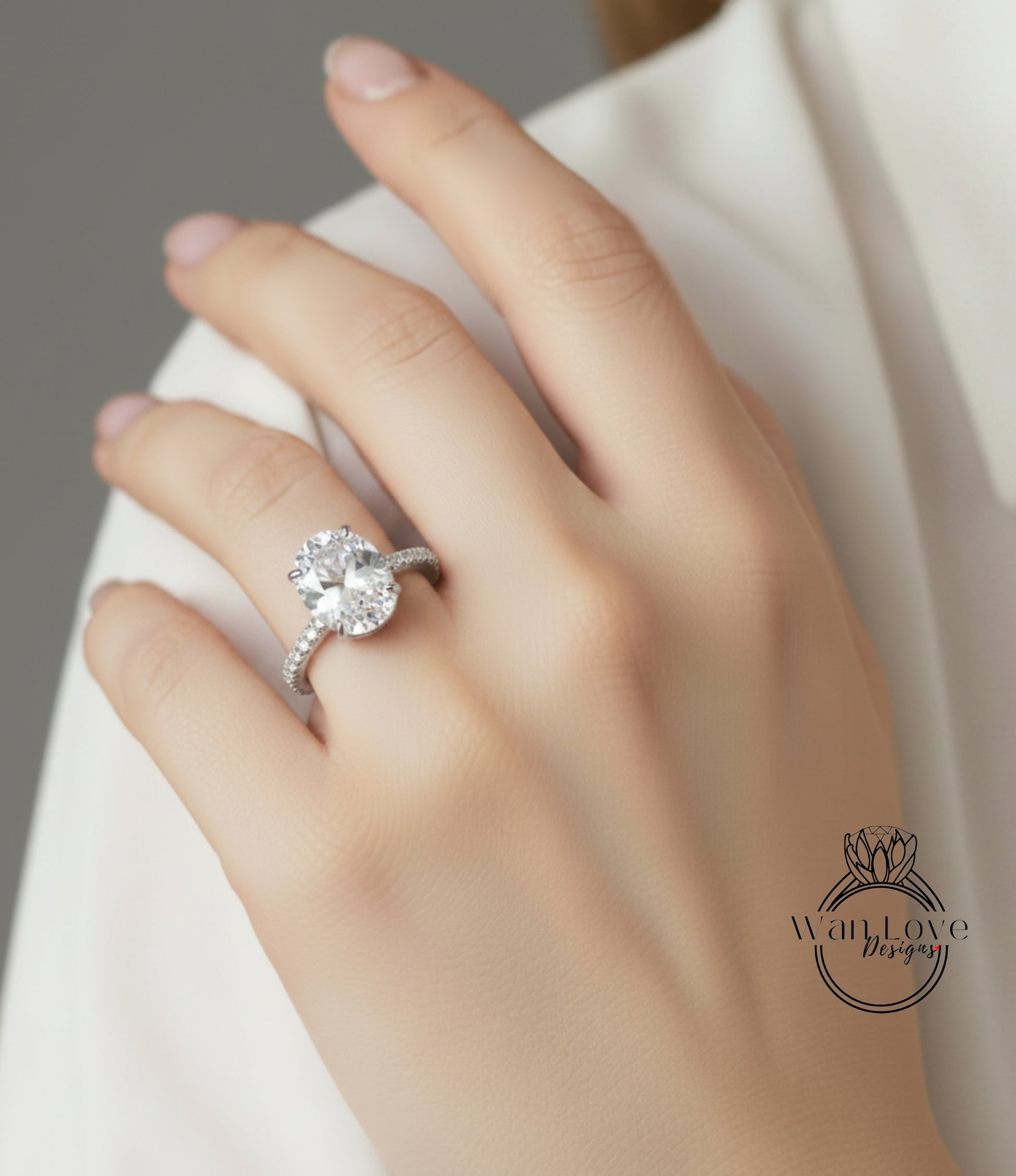 A close-up of a hand wearing a diamond engagement ring on the ring finger.