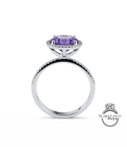 A silver ring with a large purple gemstone, likely an amethyst, set in a halo of smaller diamonds.