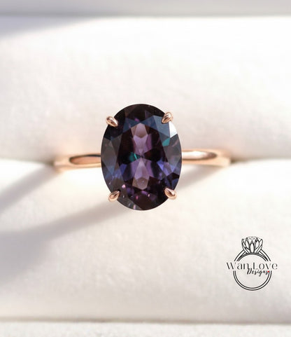 A close-up image of a gold ring with a large oval-shaped purple gemstone, placed on a white background.