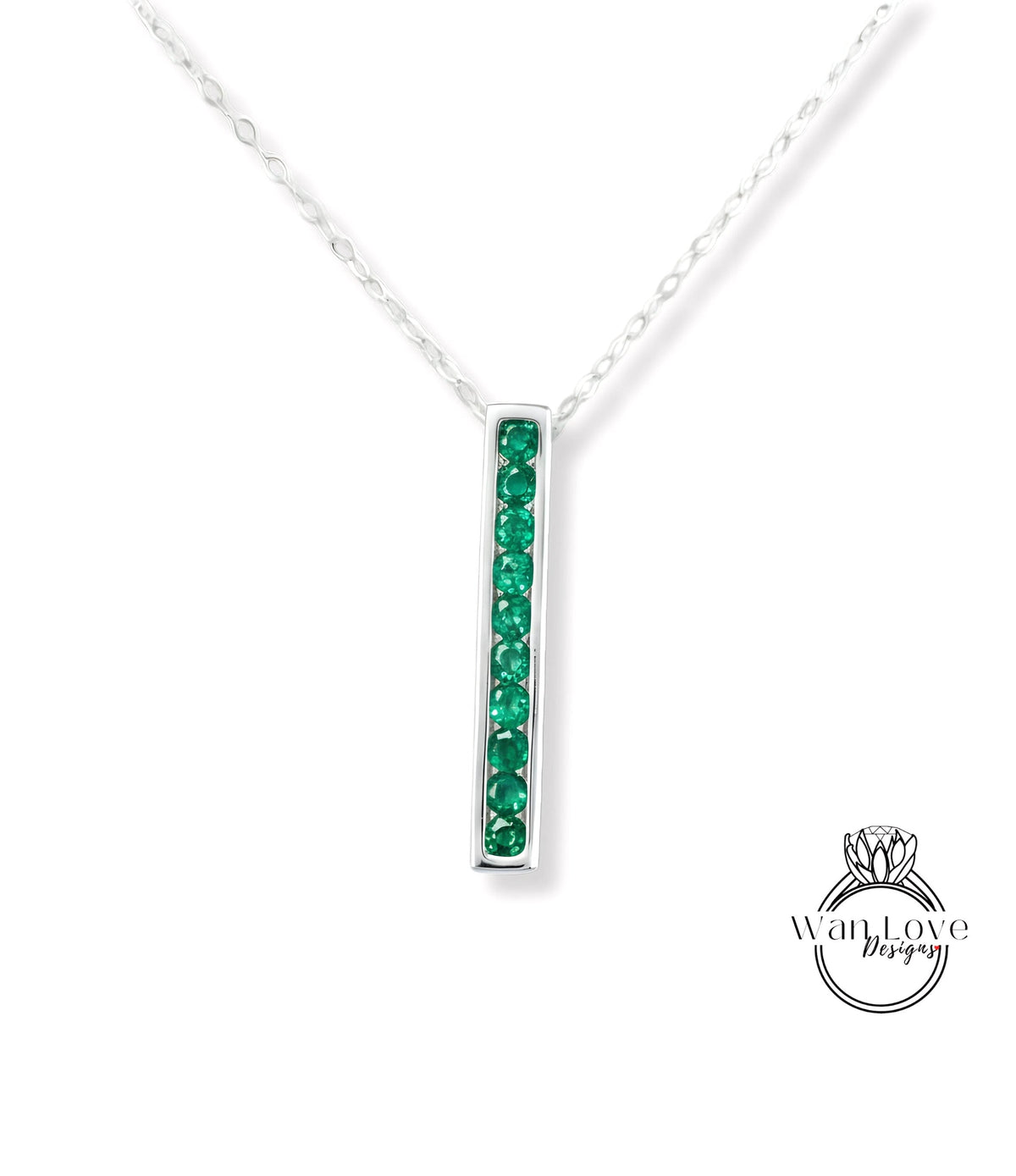 A silver necklace with a vertical rectangular pendant featuring green gemstones.