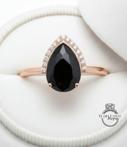 A close-up image of a gold ring with a large black gemstone, likely a diamond, set in the center of the band.