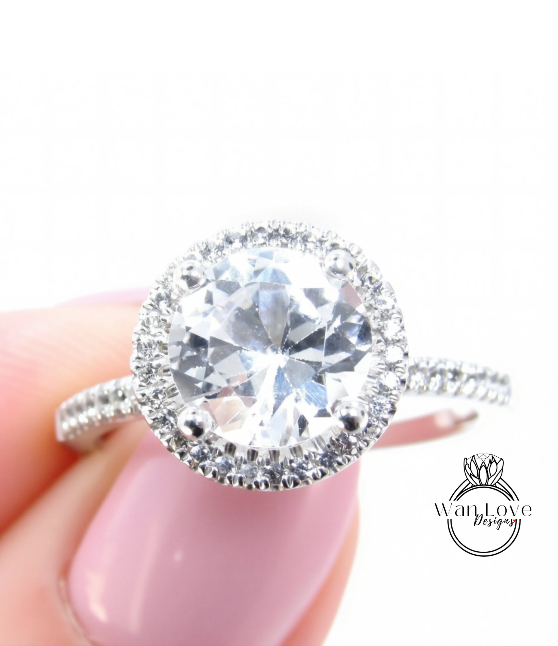 A close-up of a person's hand holding a diamond engagement ring with a large, round brilliant-cut diamond set in a halo of smaller diamonds.