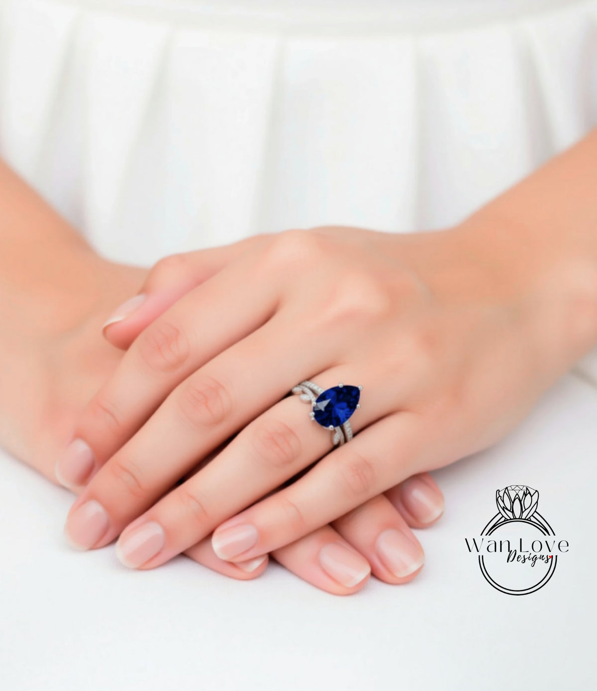 A close-up image of a person's hands wearing a ring with a large blue gemstone.