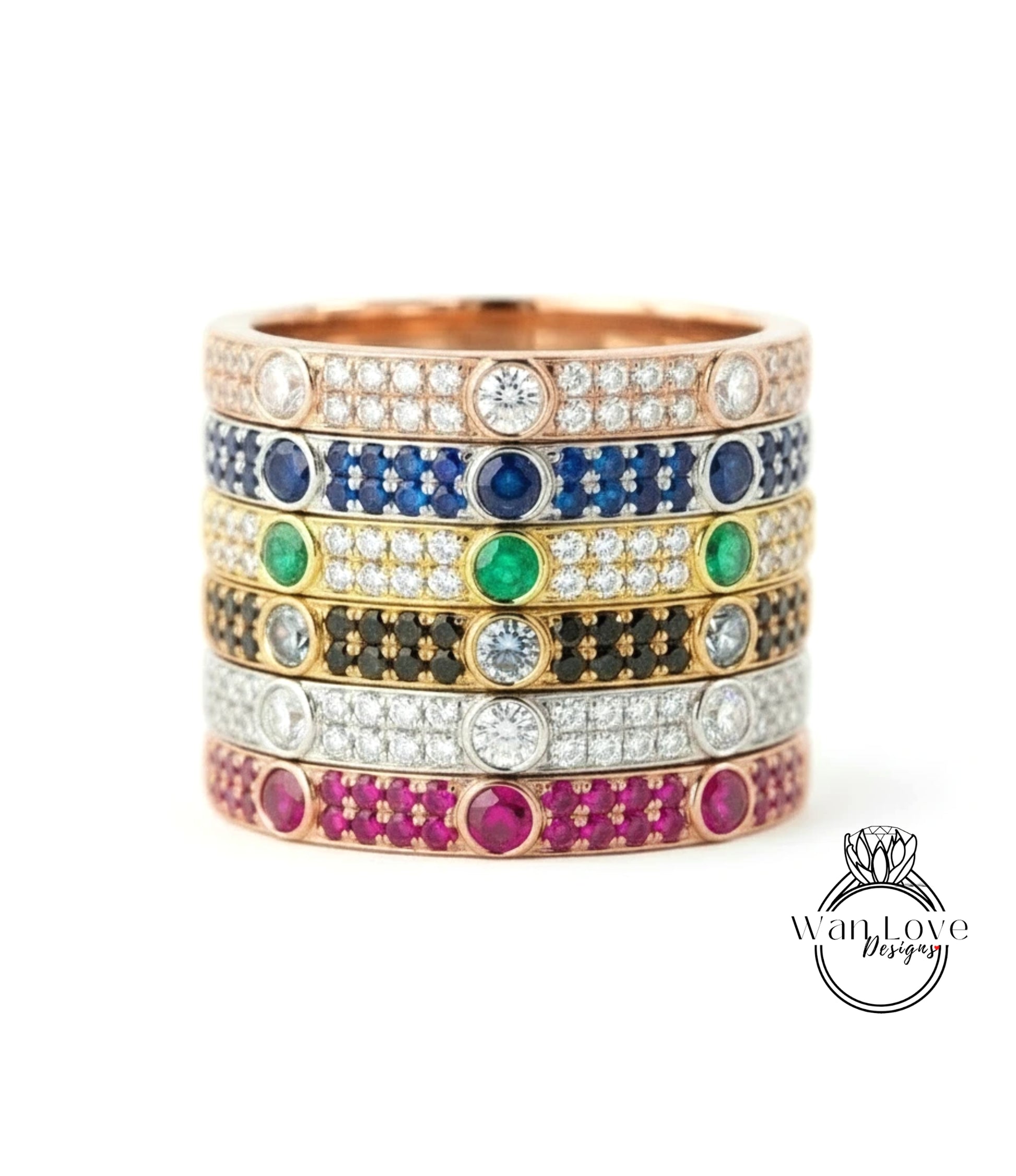 A stack of rings with various colored gemstones and diamonds set in a gold band.