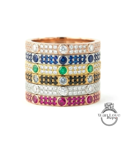 A stack of rings with various colored gemstones and diamonds set in a gold band.