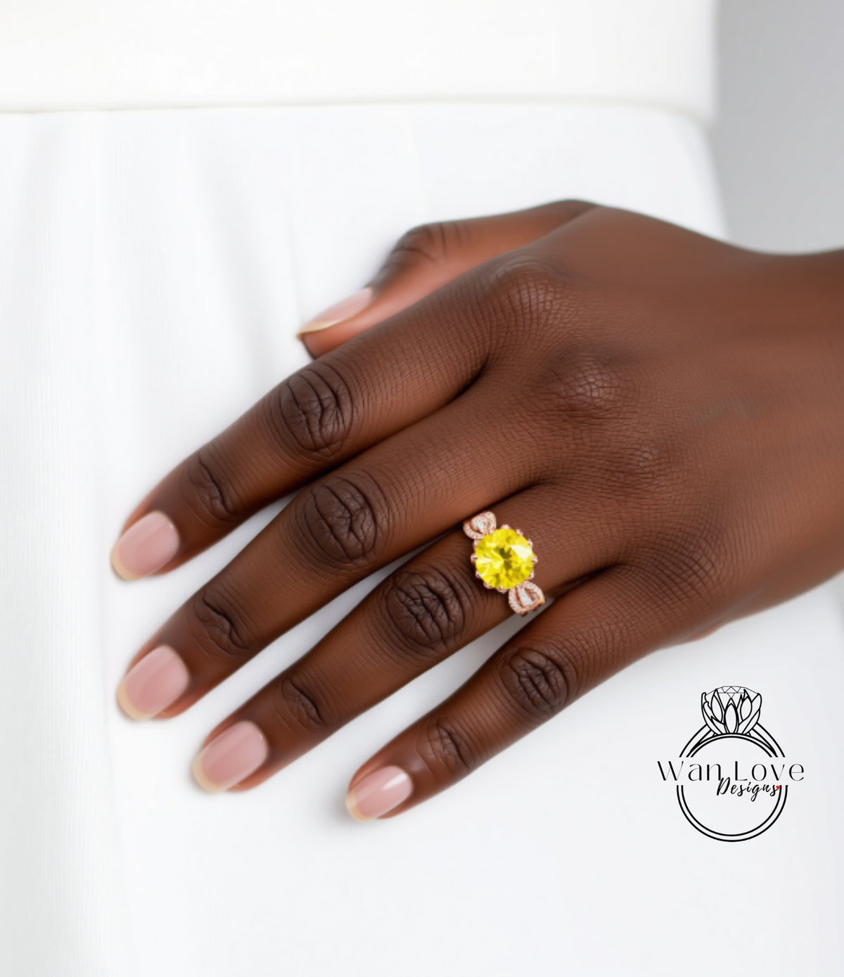 A close-up of a hand wearing a yellow gemstone ring on the ring finger.