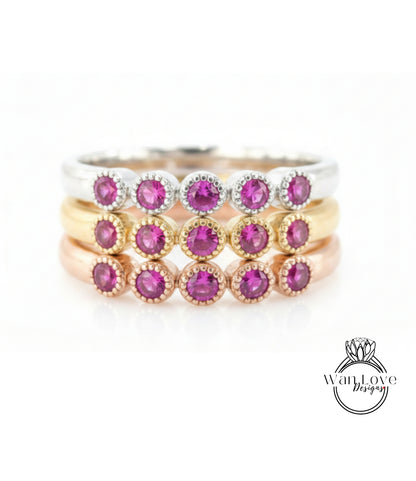 A ring with multiple layers of rings, each ring featuring a small, round, purple gemstone.