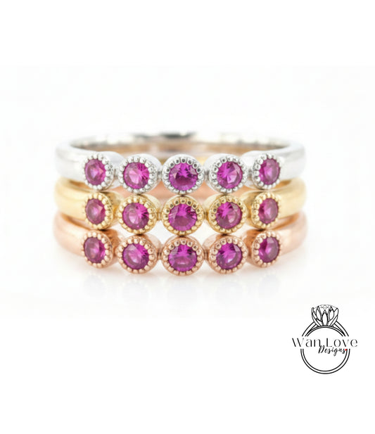 A ring with multiple layers of rings, each ring featuring a small, round, purple gemstone.