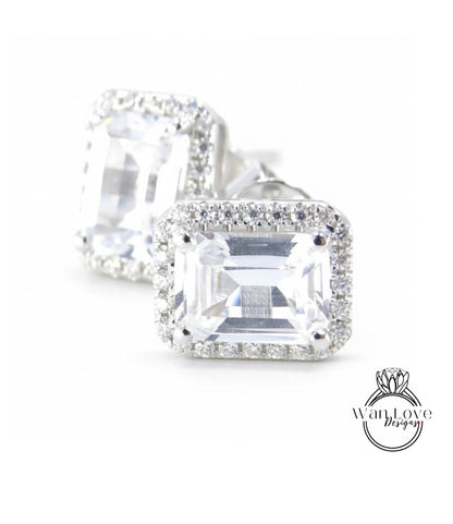 A pair of elegant diamond earrings with a large, clear gemstone set in a halo of smaller diamonds, creating a sparkling and sophisticated appearance.