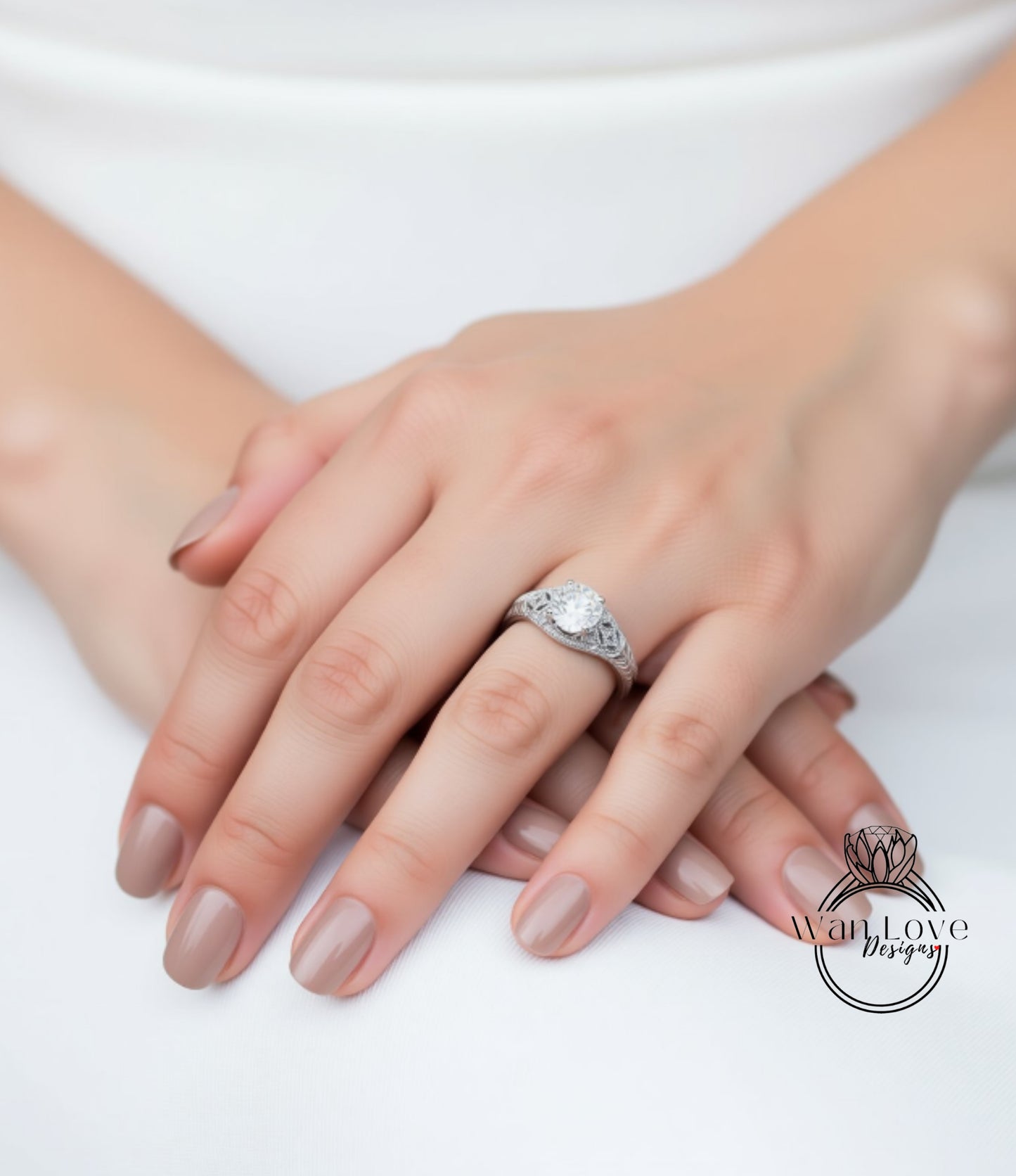 A close-up image of a person's hands with a diamond engagement ring on the ring finger.