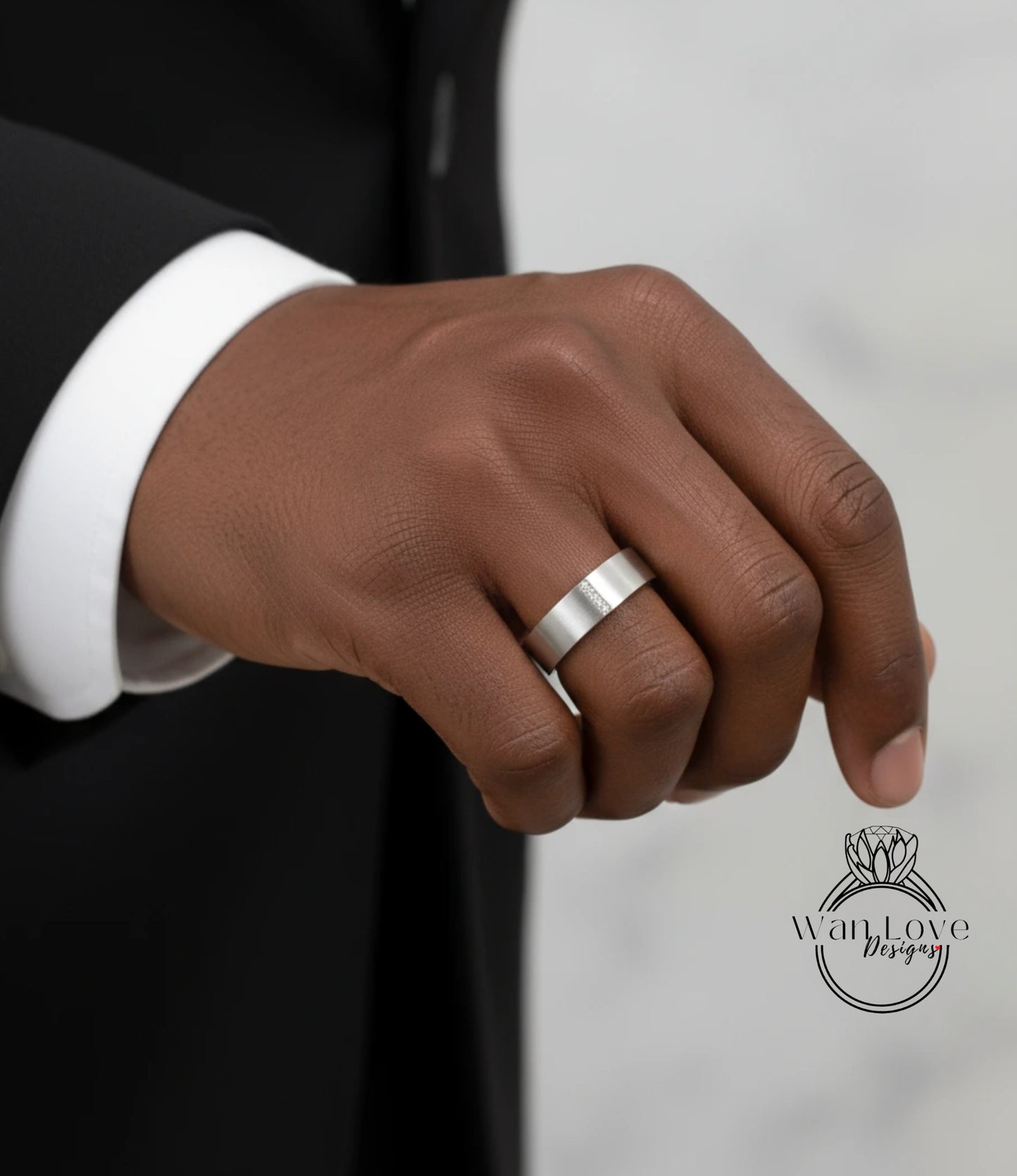 A close-up of a person's hand wearing a silver wedding ring.