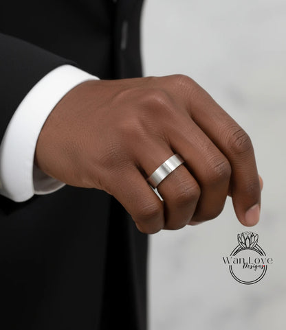 A close-up of a person's hand wearing a silver wedding ring.