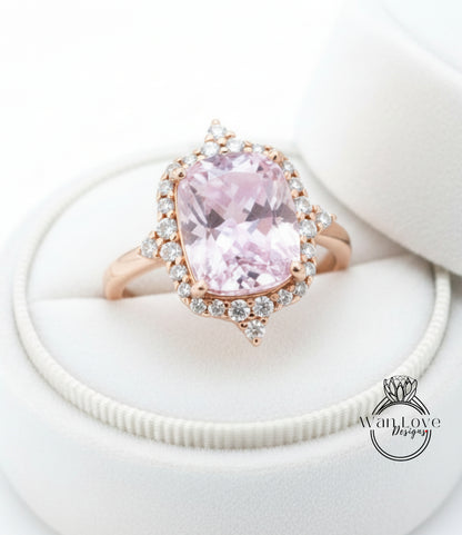 A beautiful pink gemstone ring with a halo of smaller diamonds set in a gold band, displayed in a white jewelry box.