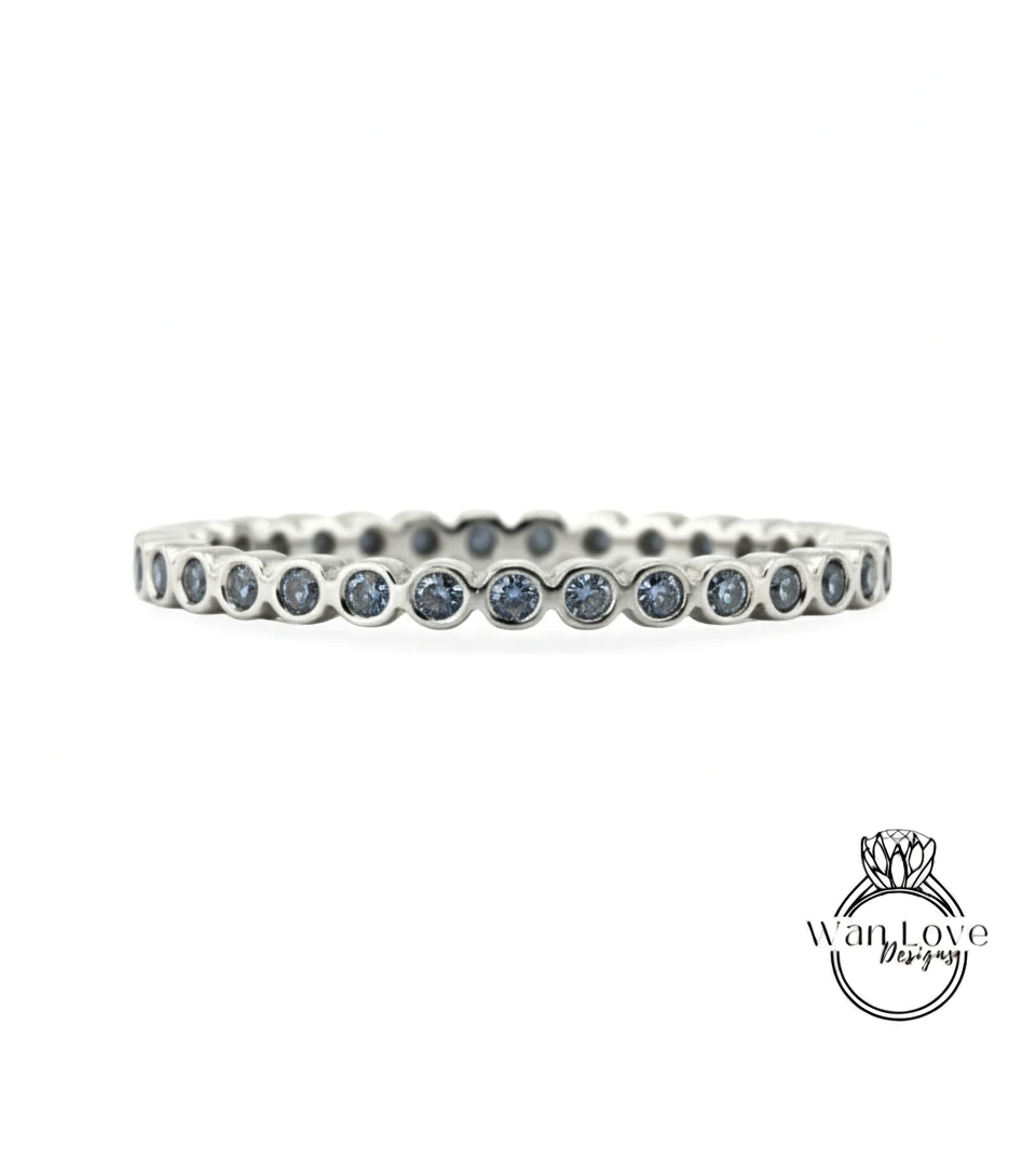 A silver band with blue gemstones, likely a ring, is shown against a white background.
