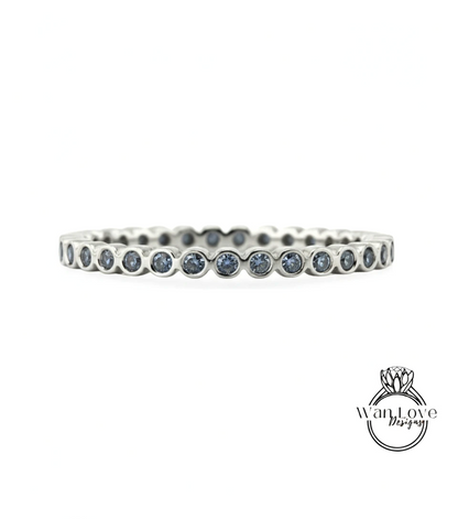 A silver band with blue gemstones, likely a ring, is shown against a white background.