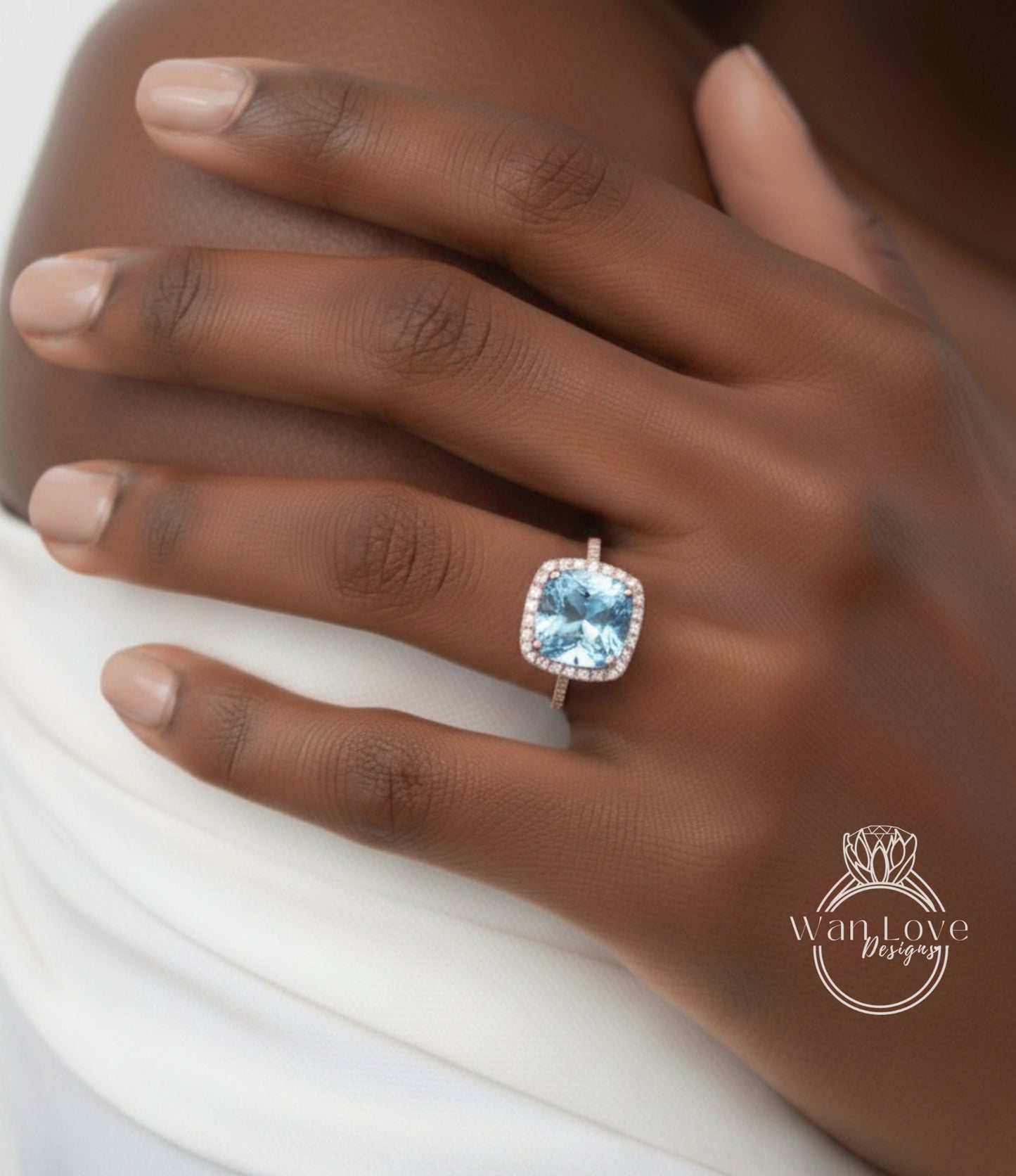 A close-up of a person's hand wearing a large, blue gemstone ring with a halo around it.