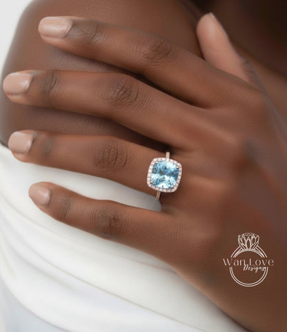 A close-up of a person's hand wearing a large, blue gemstone ring with a halo around it.