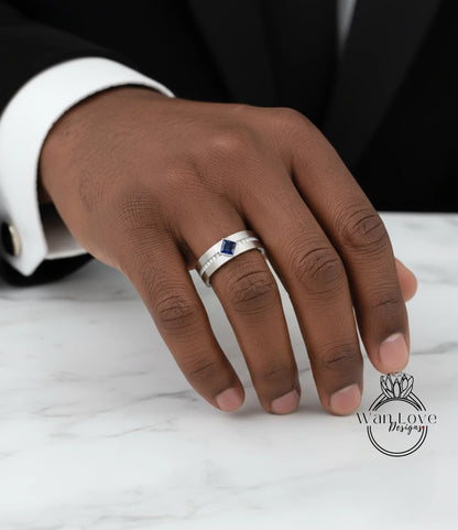 A close-up of a person's hand wearing a silver ring with a blue gemstone.