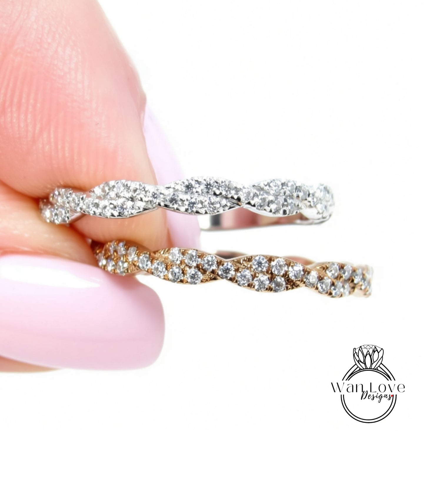 A close-up of a person's hand holding a ring with a twisted band and sparkling diamonds.