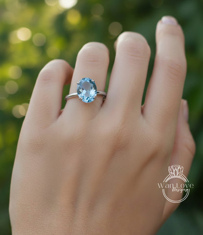 A close-up of a hand wearing a ring with a blue gemstone, likely an aquamarine or blue topaz stone.