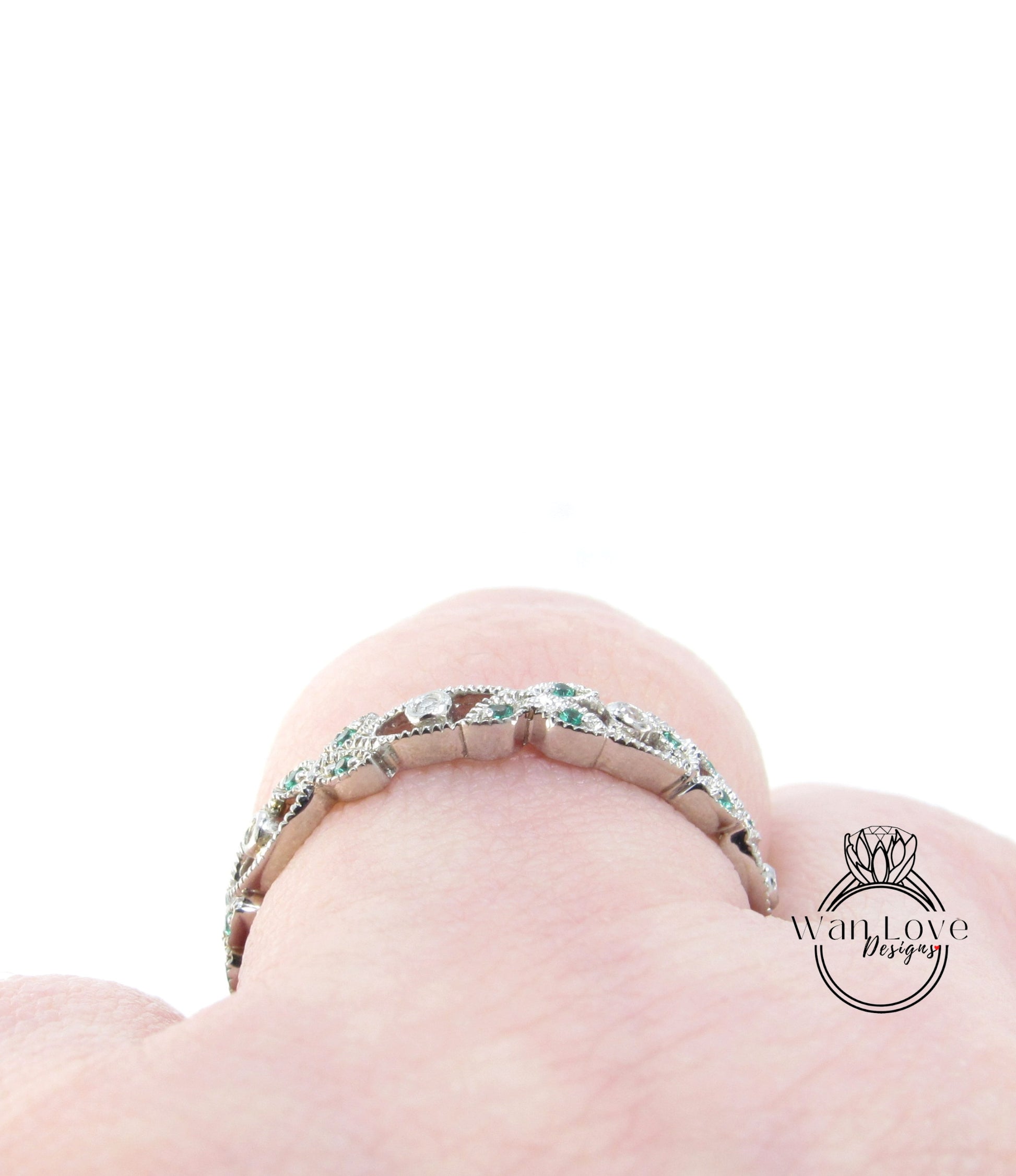 A close-up view of a silver ring with green gemstones on a person's finger.