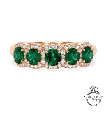 A rose gold ring with a row of green gemstones, including diamonds, set in the center.