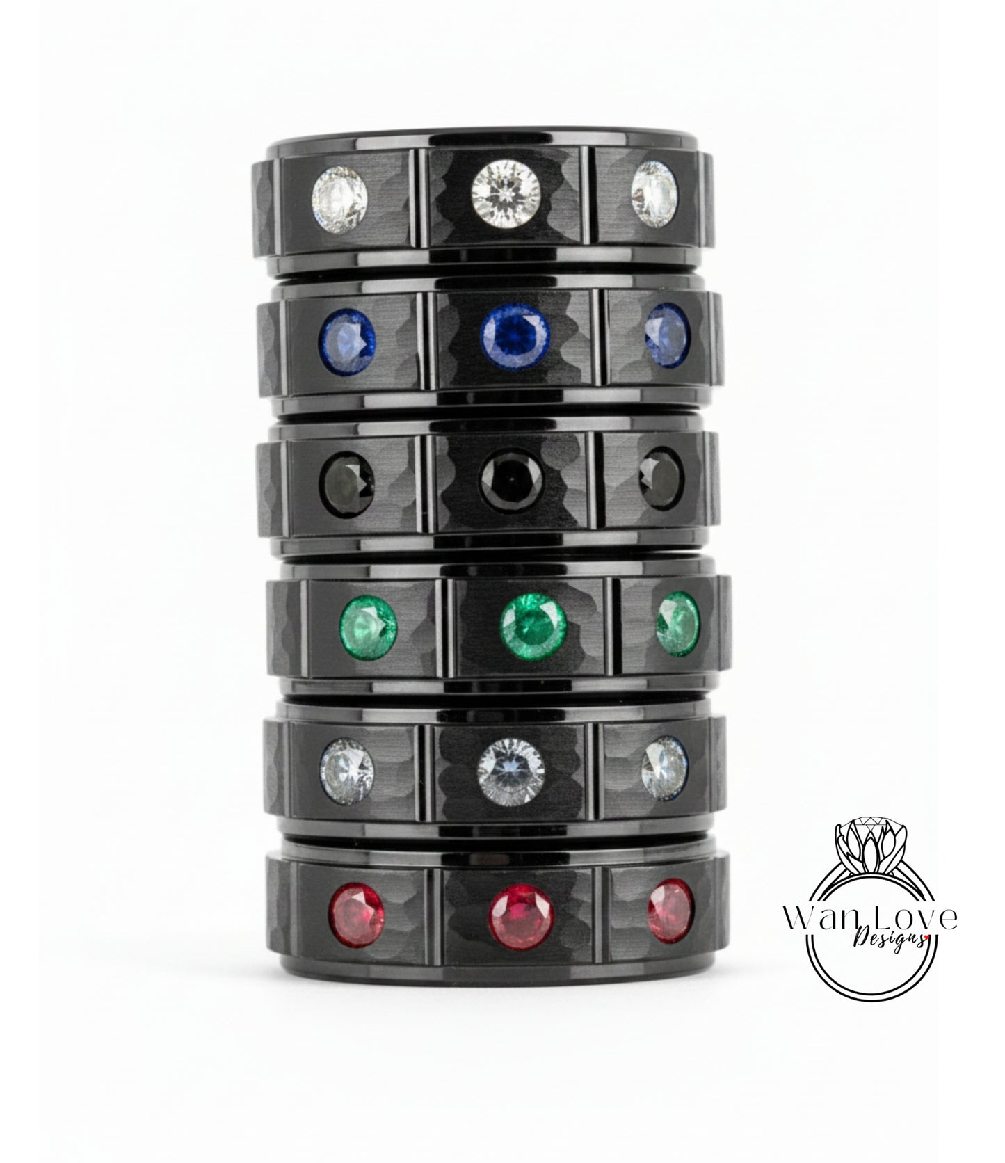 A stack of black rings with various colored gemstones, including diamonds, set in the center of each ring.