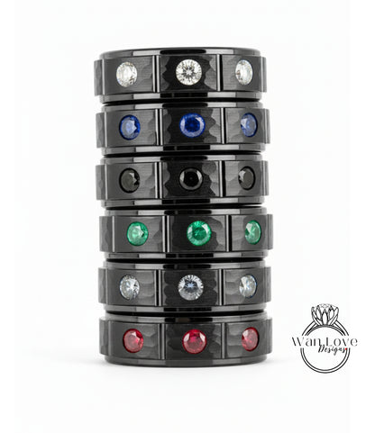 A stack of black rings with various colored gemstones, including diamonds, set in the center of each ring.