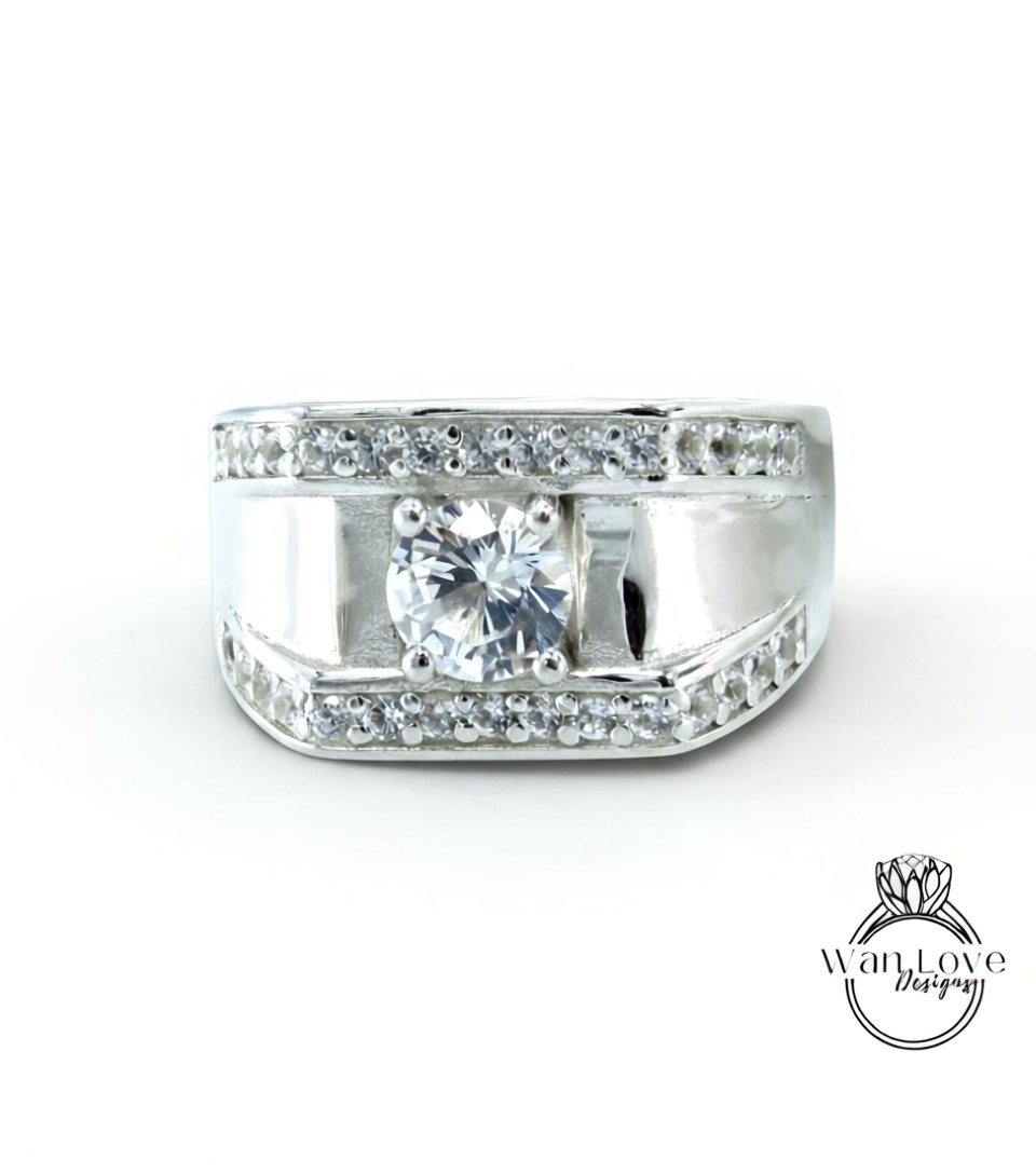 A silver ring with a large central diamond and smaller diamonds around the edges, set in a band.
