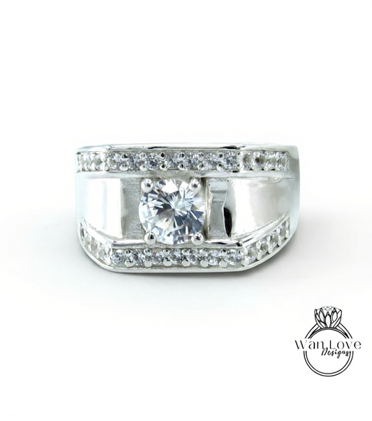 A silver ring with a large central diamond and smaller diamonds around the edges, set in a band.