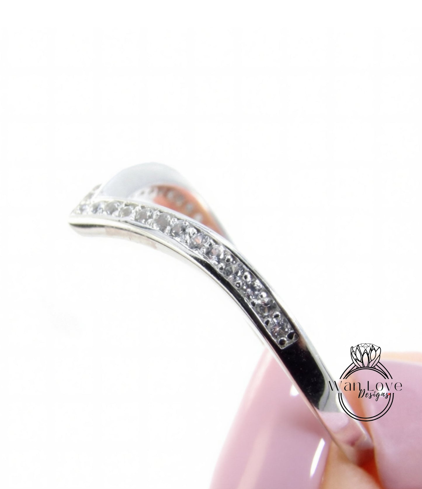 A close-up view of a silver ring with a curved band adorned with small diamonds.