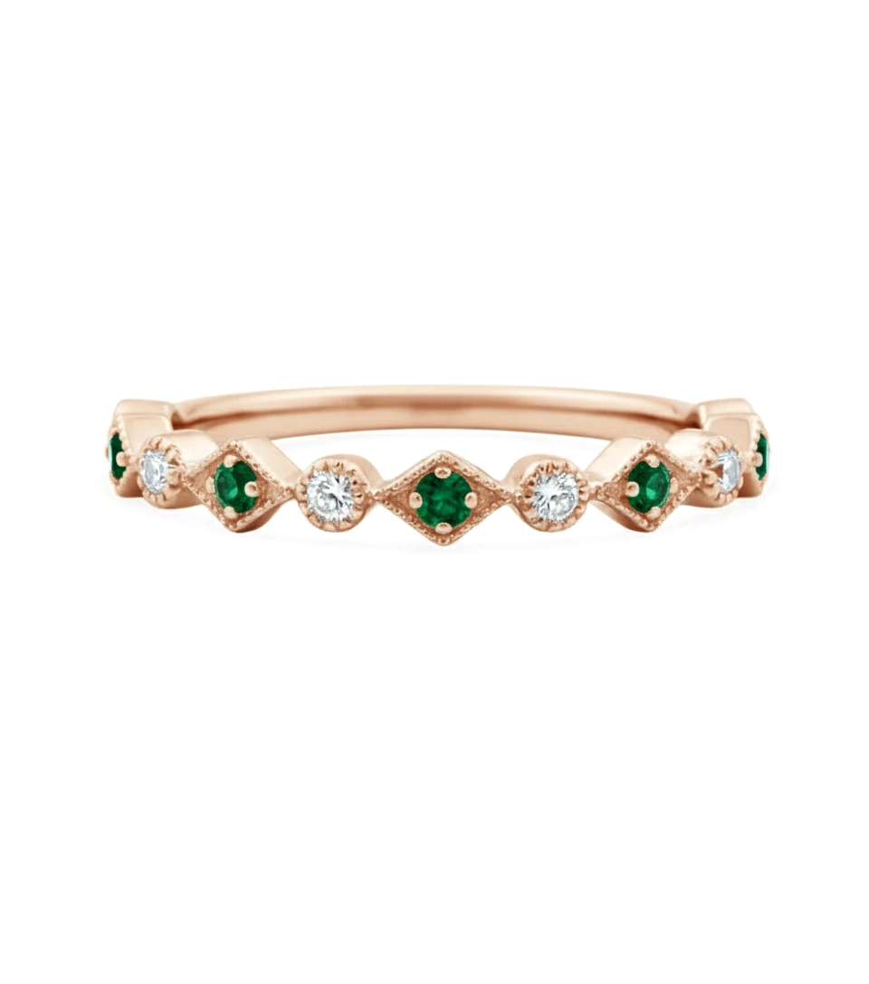 A rose gold ring with a row of diamonds and green gemstones.