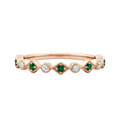 A rose gold ring with a row of diamonds and green gemstones.