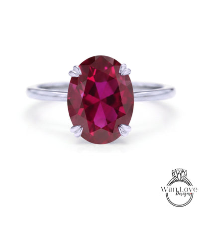 A close-up image of a ring with a large, deep red gemstone, likely a garnet, set in a silver band.