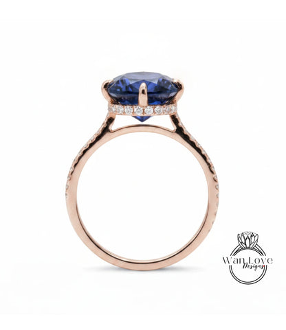 A rose gold ring with a large blue gemstone set in the center, surrounded by smaller diamonds.