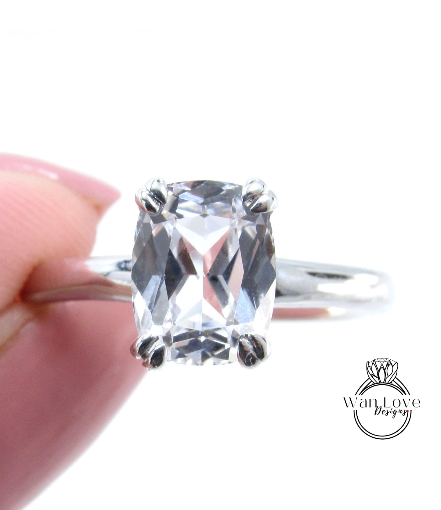 A close-up image of a person's hand holding a diamond engagement ring with a large, clear gemstone.