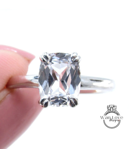 A close-up image of a person's hand holding a diamond engagement ring with a large, clear gemstone.