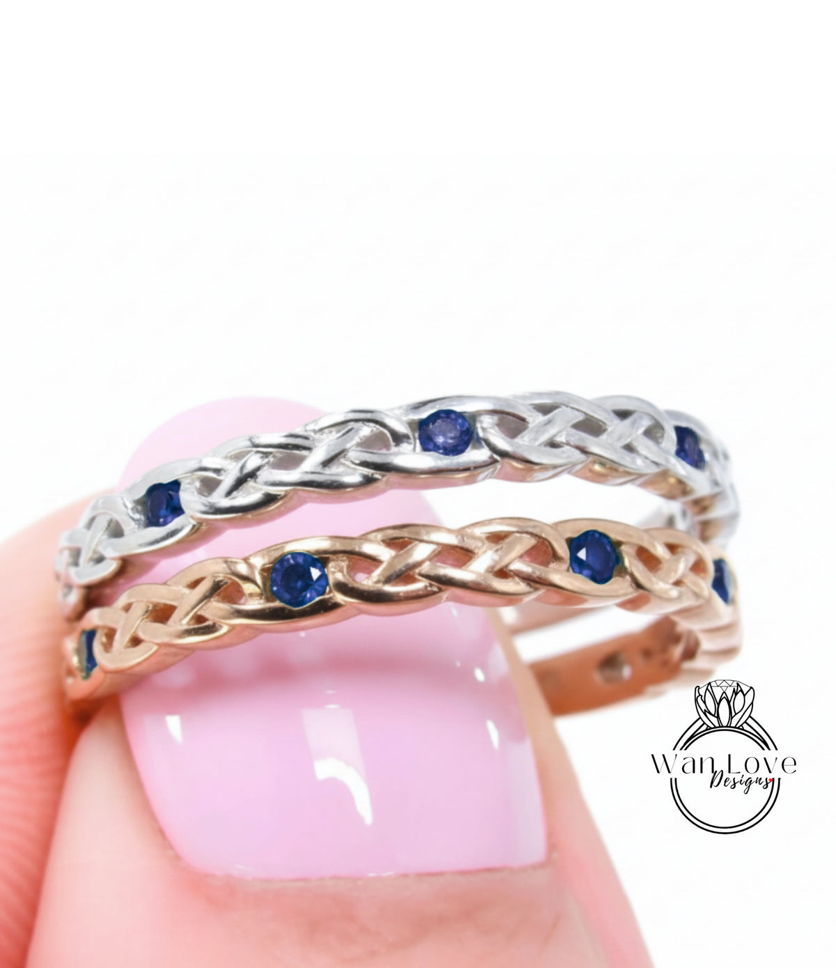 A close-up of a person's hand wearing a silver and gold ring with blue gemstones.