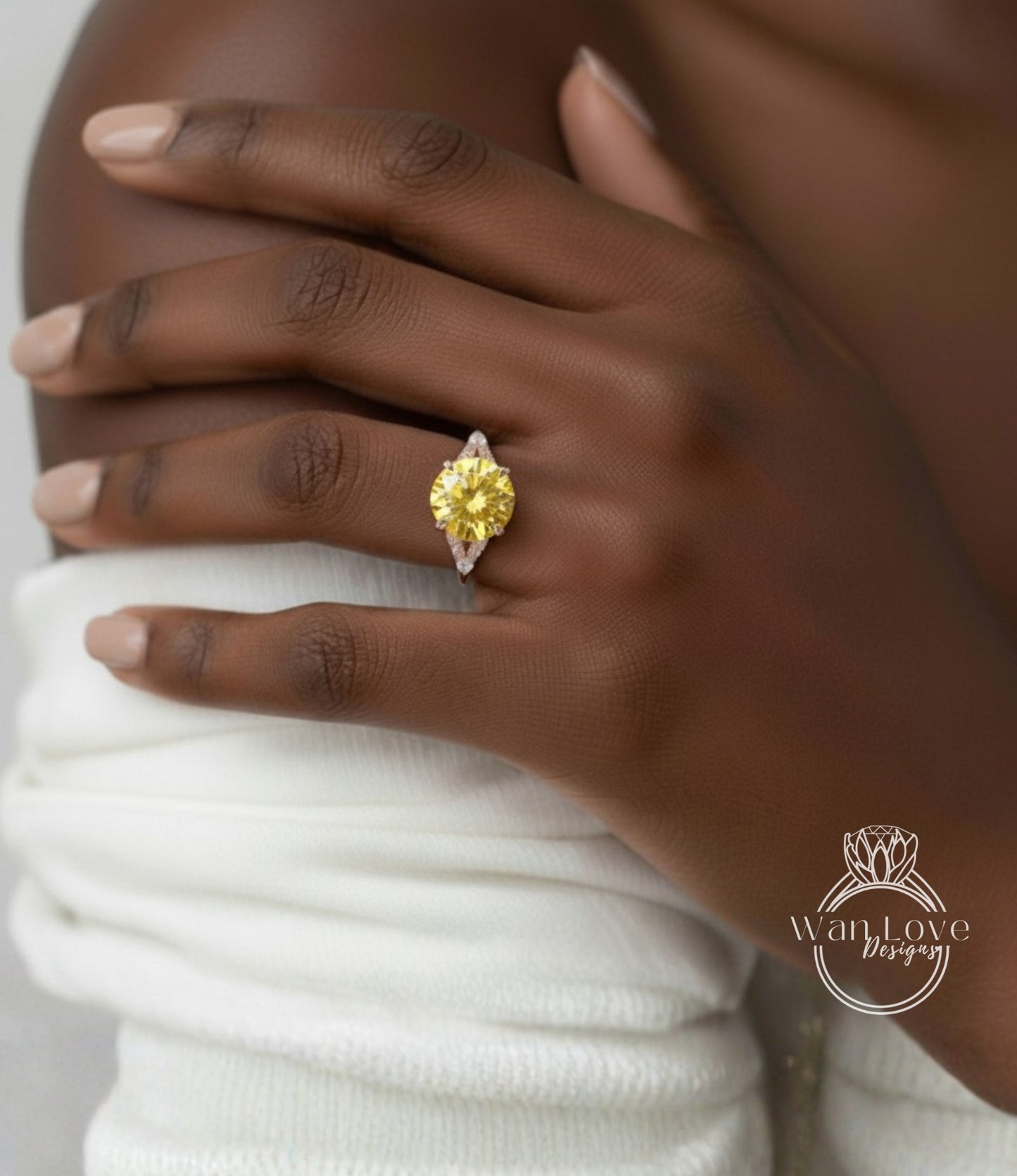 A close-up of a person's hand wearing a yellow diamond ring on the ring finger.