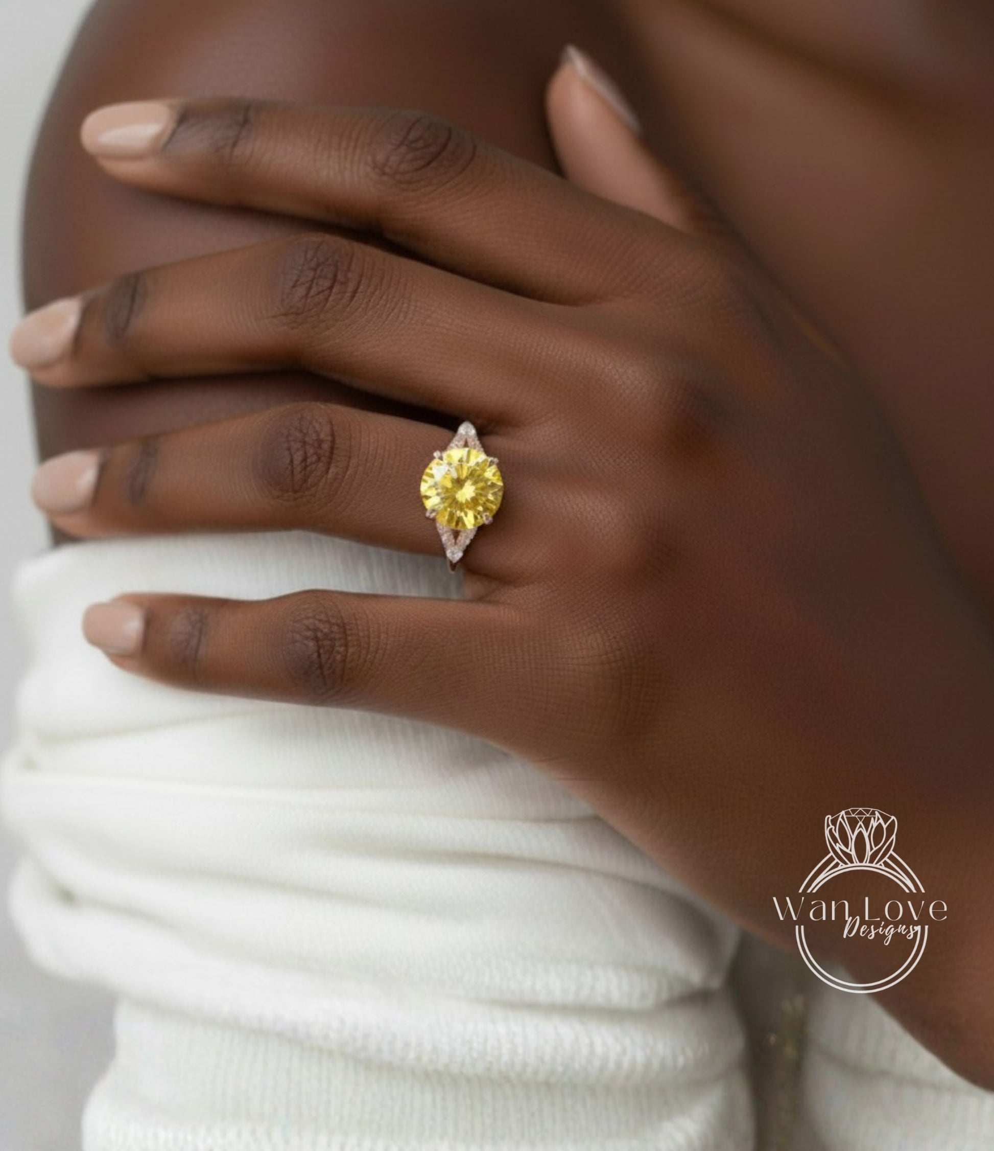 A close-up of a person's hand wearing a yellow diamond ring on the ring finger.