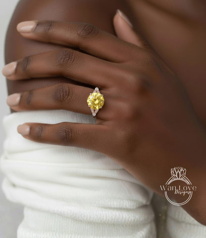 A close-up of a person's hand wearing a yellow diamond ring on the ring finger.