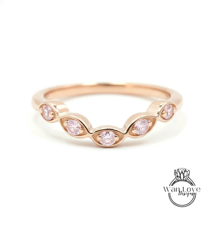 A rose gold ring with a row of small pink gemstones set in the center.