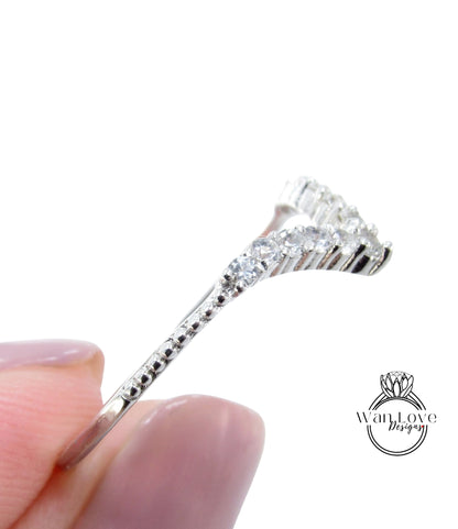 A close-up image of a person's hand holding a silver ring with a row of small diamonds on the band.