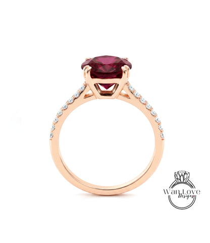A gold ring with a large, deep red gemstone set in the center, surrounded by smaller diamonds.