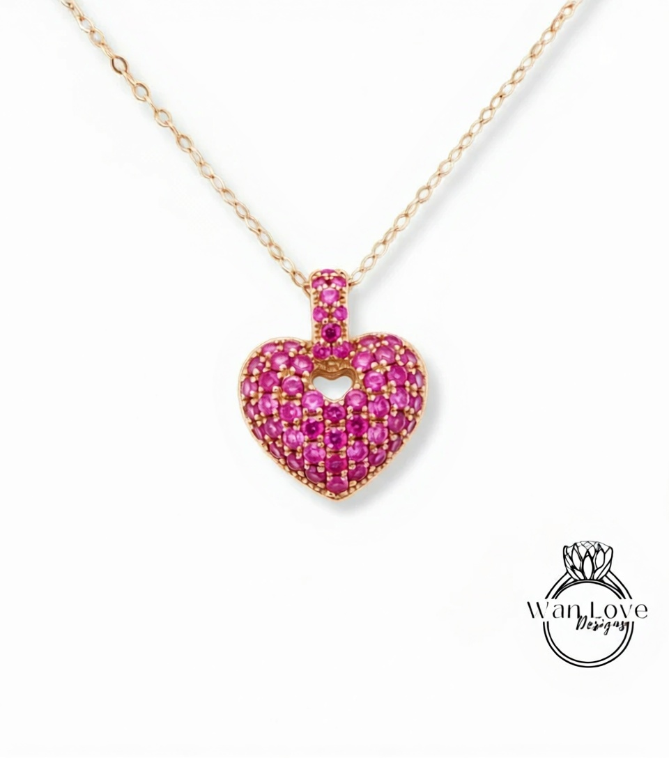 A delicate gold necklace with a heart-shaped pendant made of small, pink gemstones.