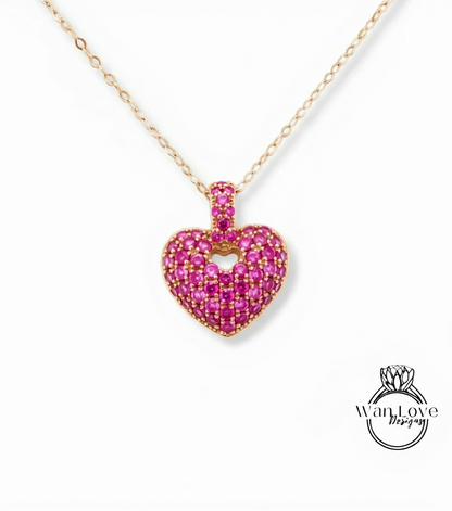 A delicate gold necklace with a heart-shaped pendant made of small, pink gemstones.