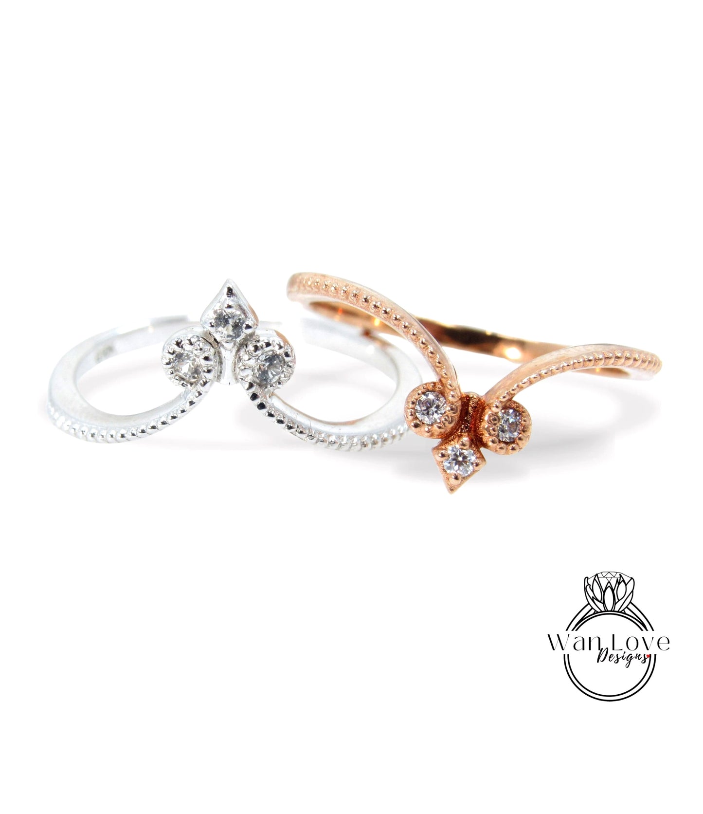 two rings with diamond-encrusted designs, one silver and one gold, against a white background.