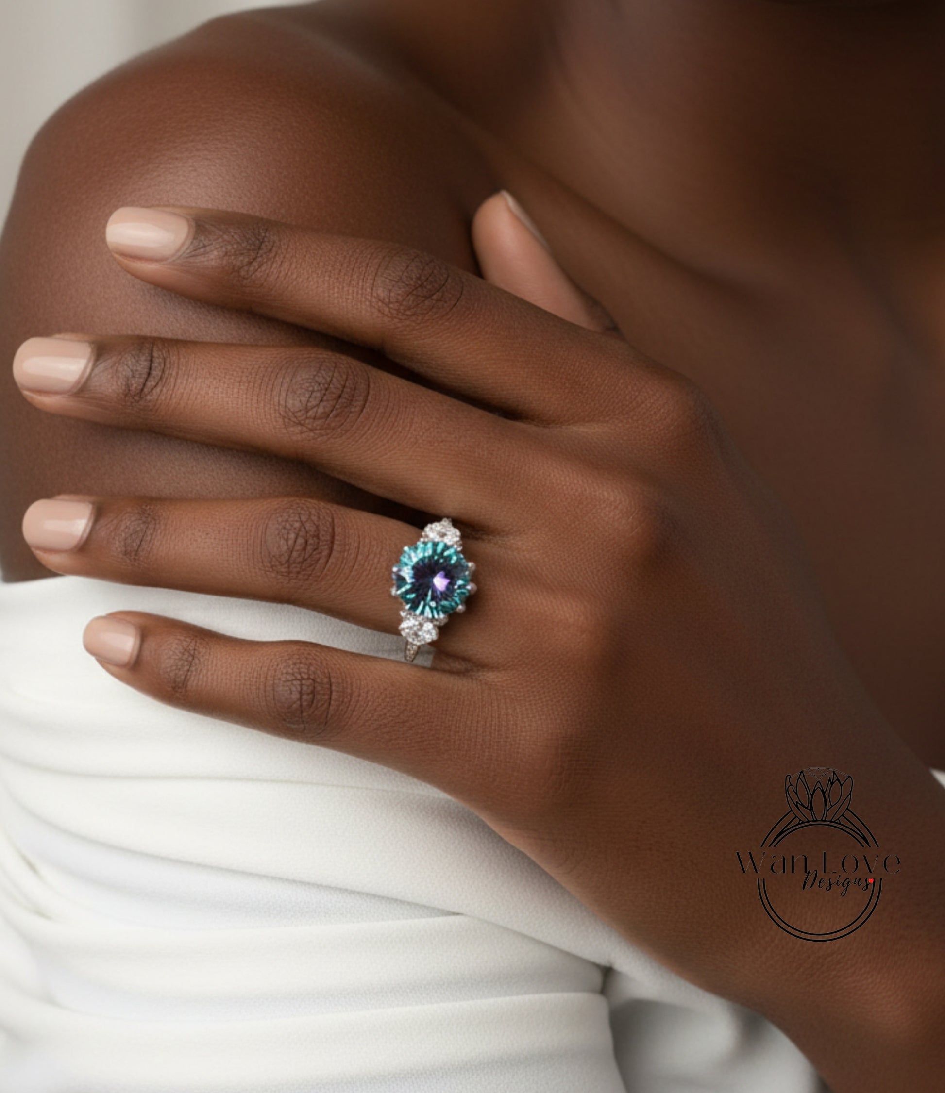 A close-up of a person's hand wearing a ring with a blue gemstone, resting on a white fabric.