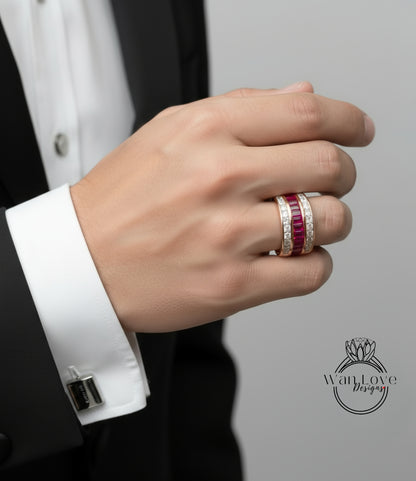 A close-up of a person's hand wearing a ring with a large gemstone, likely a diamond, and a smaller gemstone. The person is dressed in a black suit and white shirt.